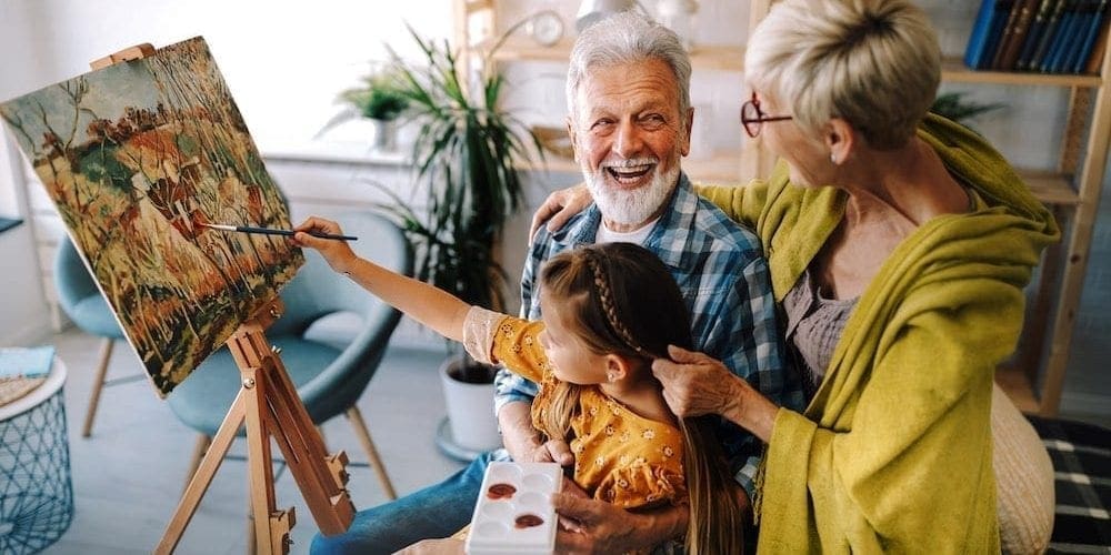 Happy smiling grandparents and grandchild painting together. Family, generation, happiness concept Happy smiling grandparents and grandchild painting together. Family, generation, happiness concept