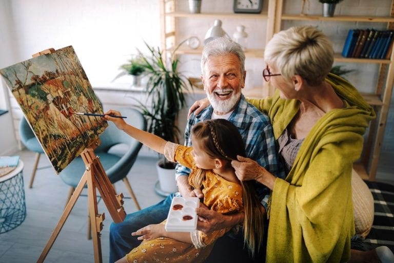 Happy smiling grandparents and grandchild painting together. Family, generation, happiness concept